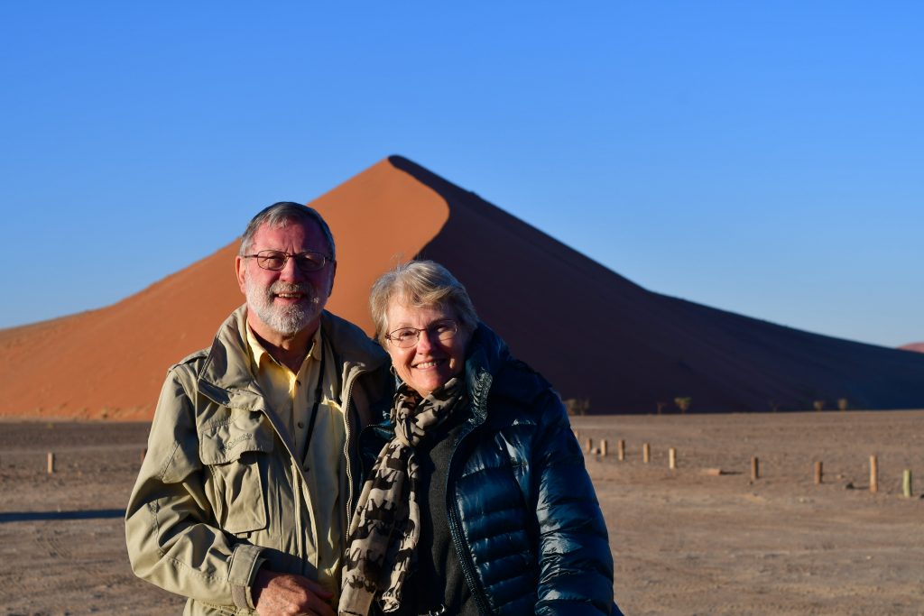 Dr. Gerald Hanson and his wife, Sue, pose in front of sand dunes during their travels in Namibia.
